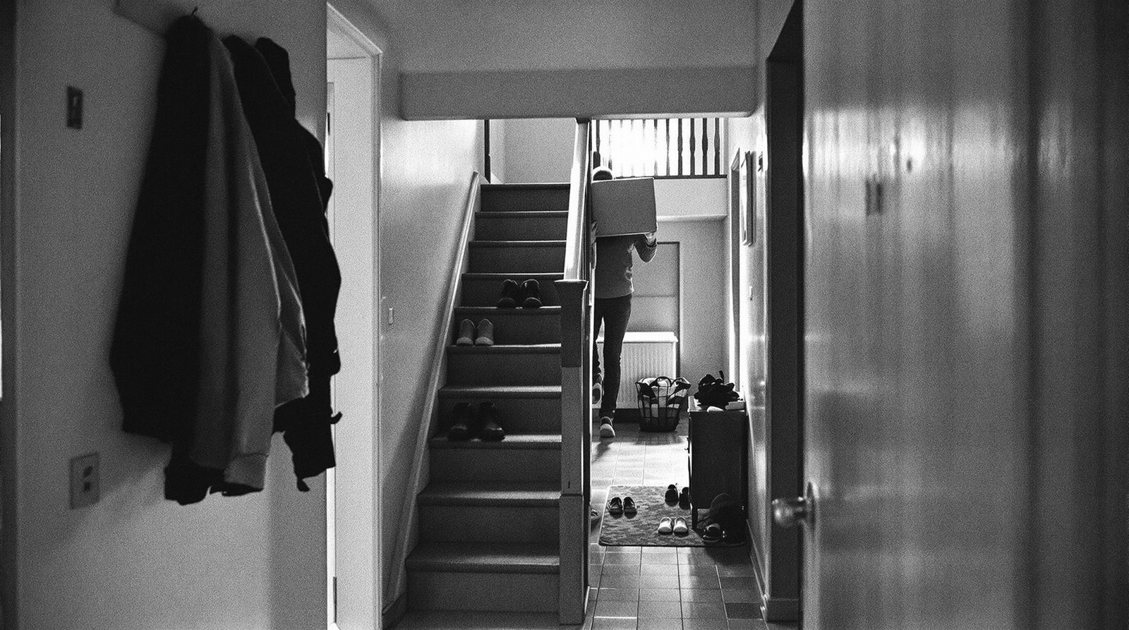 Hausflur eines Wohnhauses, jemand trägt eine Kiste die Treppe hinauf