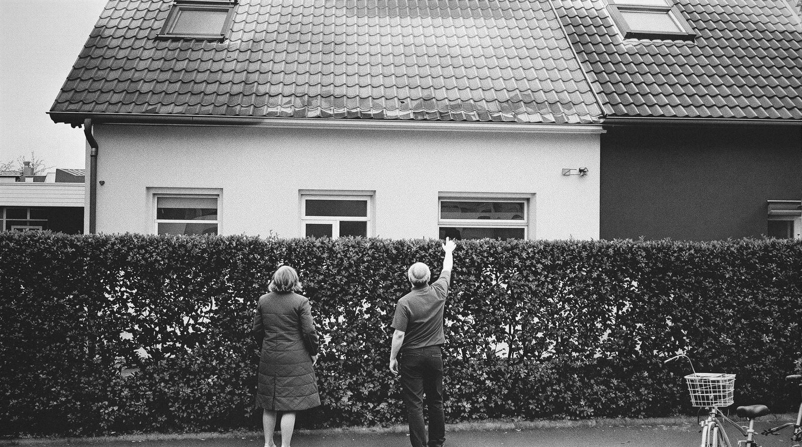 Zwei Menschen stehen vor einem Wohnhaus und schauen zum Dach hinauf